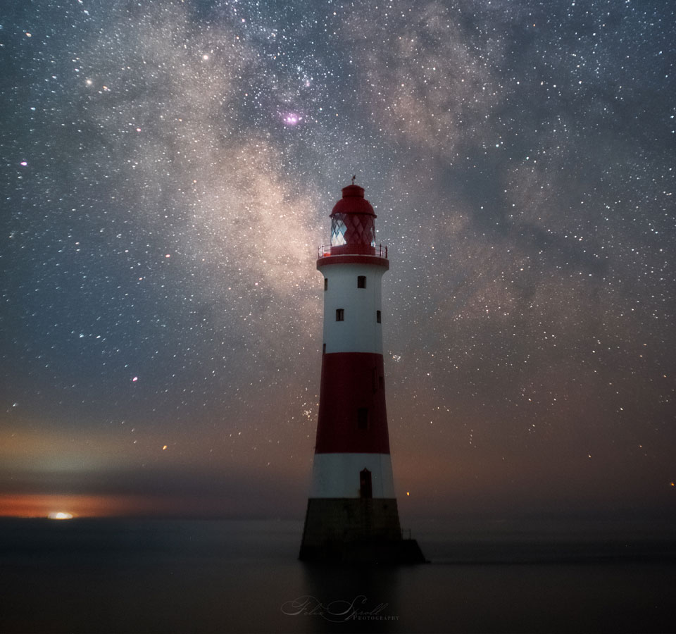 image of a lighthouse, red and white at night time with milky way